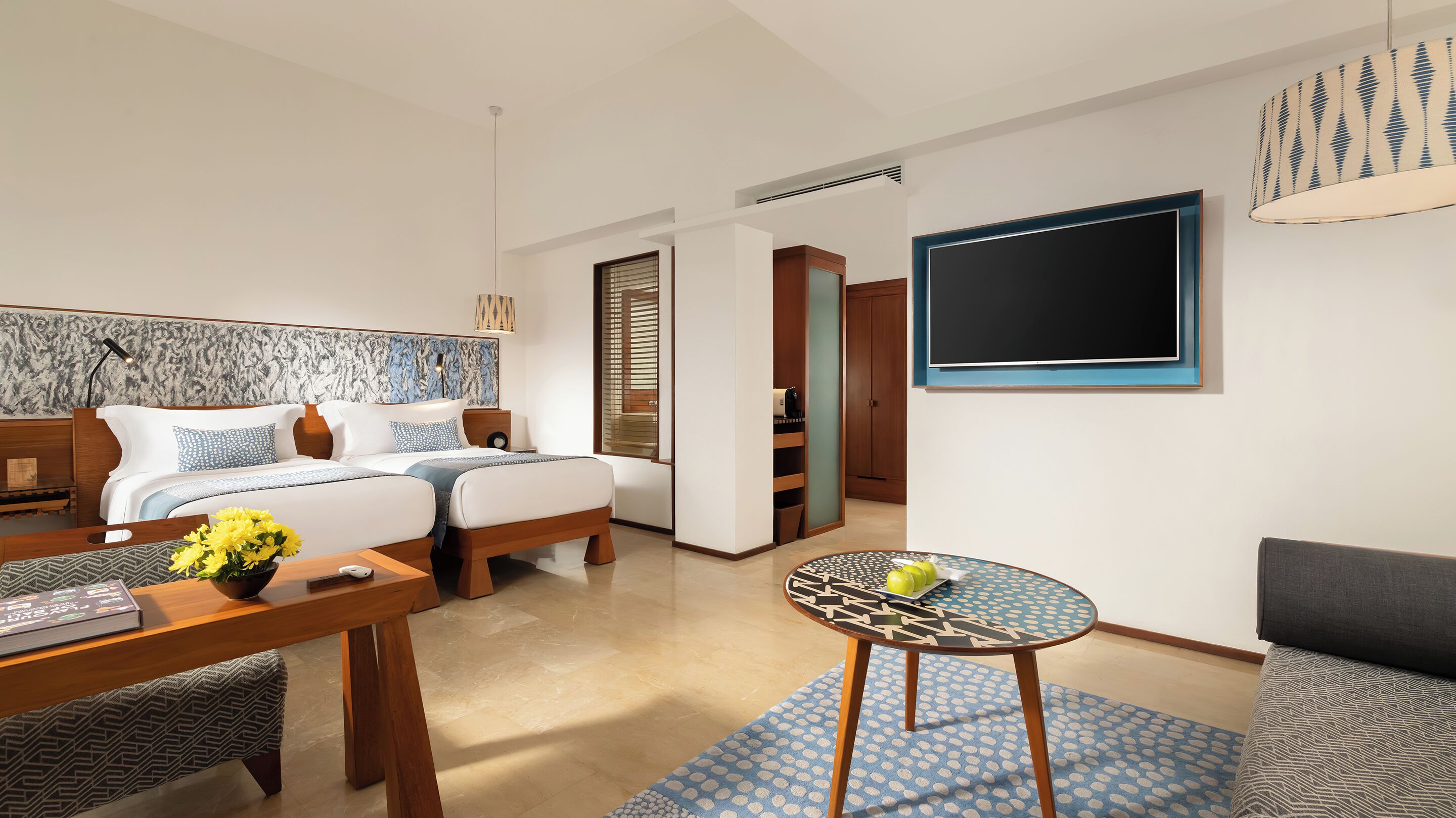 Une chambre d’hôtel moderne équipée d’un lit, d’un bureau, d’une chaise, d’une table ronde et d’un téléviseur.