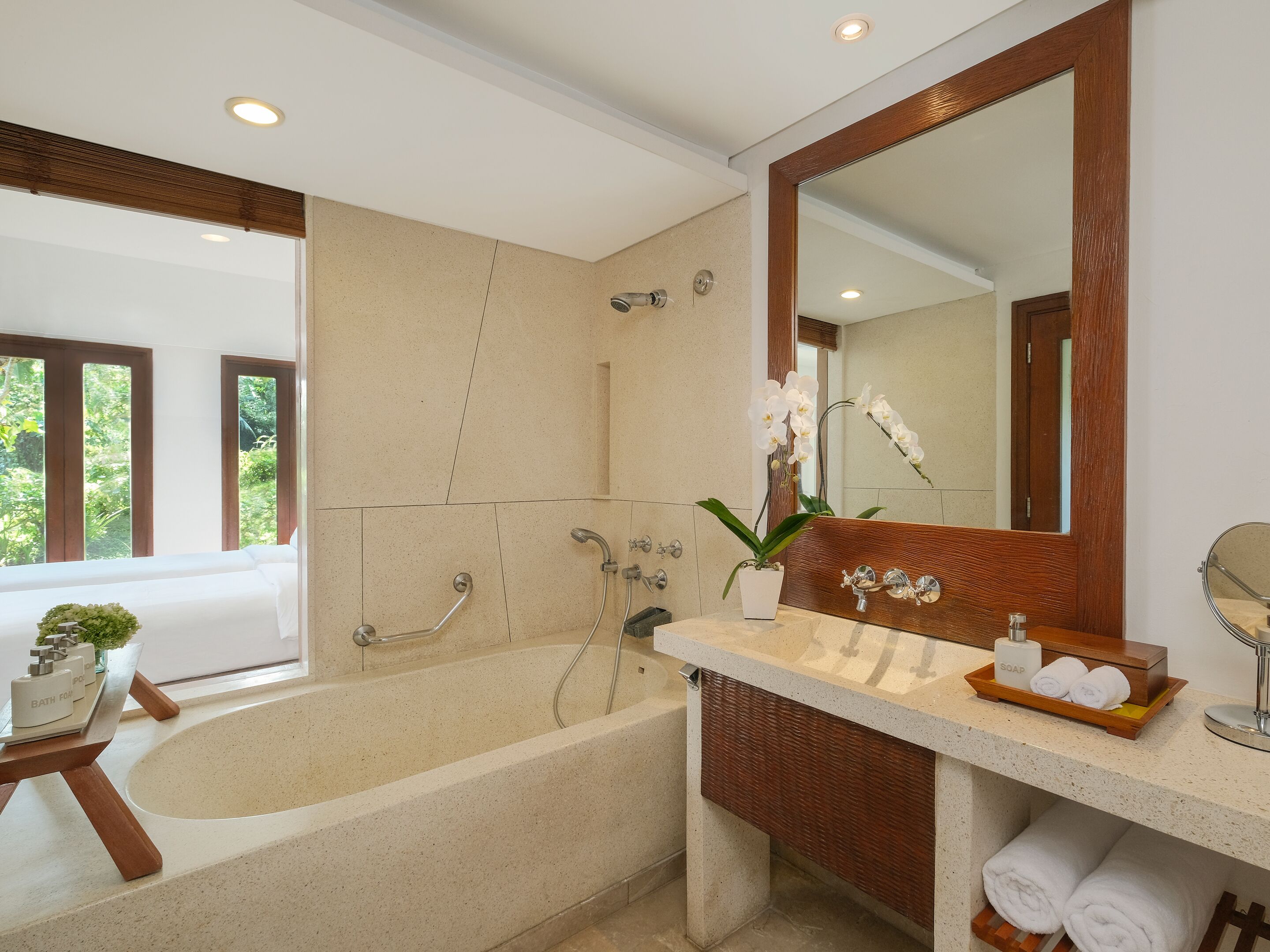 A modern bathroom with a freestanding bathtub, a large mirror, and a vanity with a soap dish and towels.