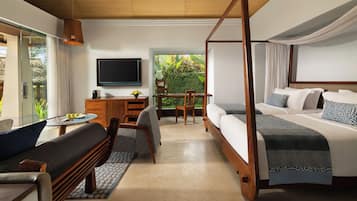 A hotel room with a four-poster bed, a desk with a chair, a sofa, and a TV on the wall.