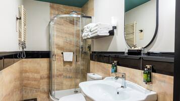 Ein modernes Badezimmer mit einer Glaskabine zur Dusche, einem weißen Waschbecken und einer Toilette.