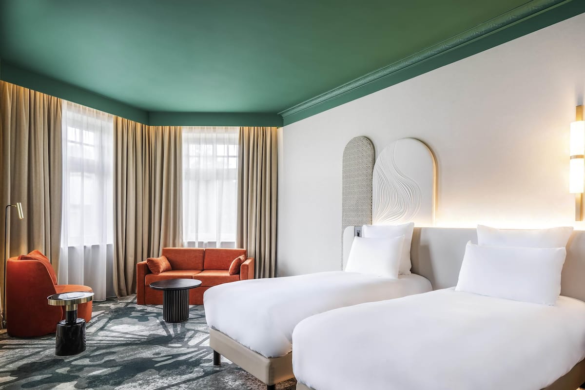 A hotel room with a bed, two sofas, a coffee table, and a large window with curtains.