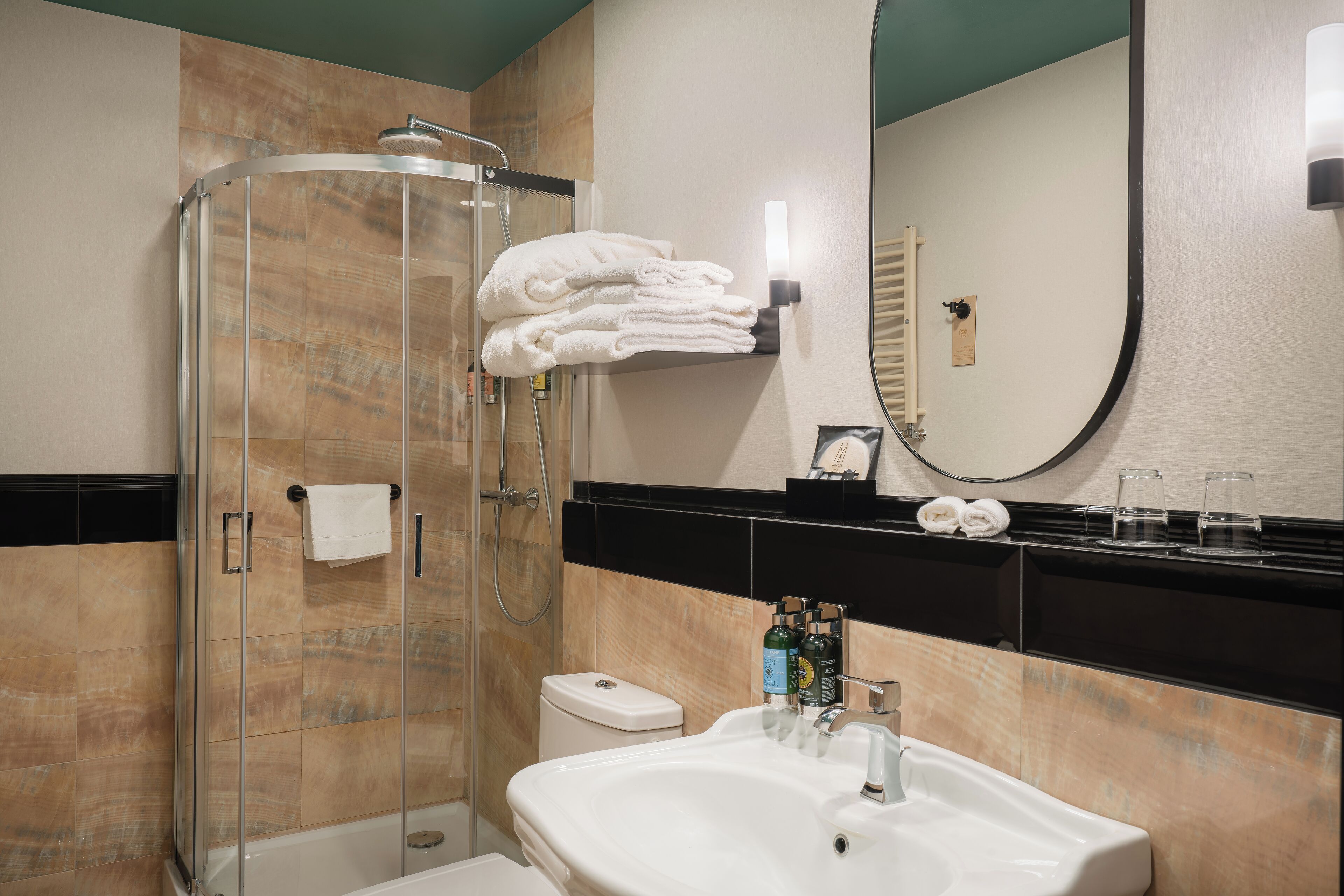 A modern bathroom with a glass-enclosed shower, a white sink, and a large mirror.