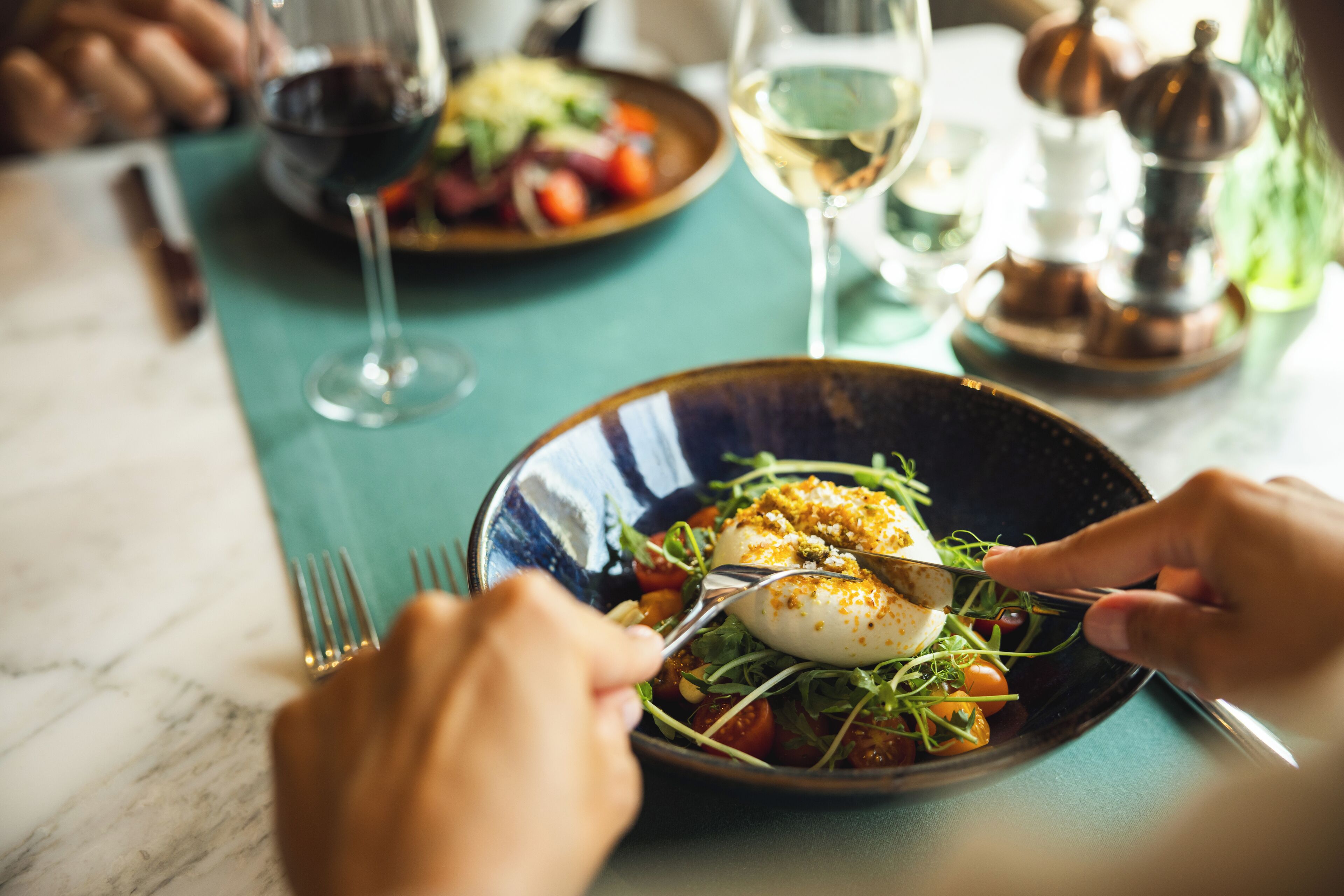 Une table à manger avec une assiette de nourriture, une fourchette et un verre de vin.