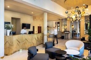 A modern lobby with a reception desk, seating area, and a staircase. - Rezydent Hotel Sopot - MGallery Collection (Sopot)