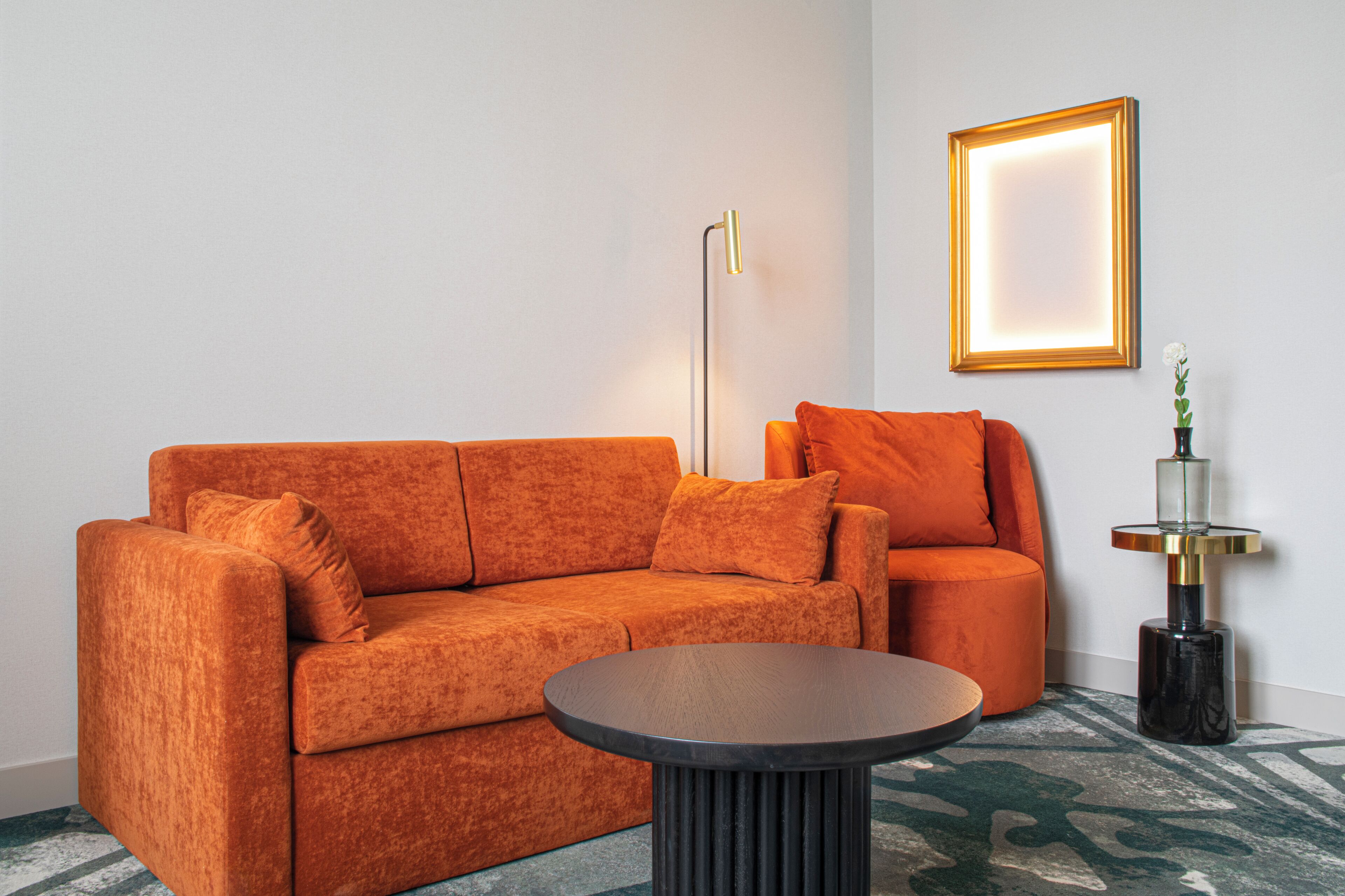 A modern living room with a sofa, a coffee table, a floor lamp, and a framed picture on the wall.