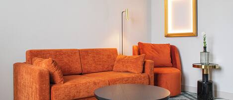 A modern living room with a sofa, a coffee table, a floor lamp, and a framed picture on the wall.