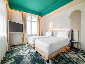 A hotel room with two beds, a TV, a bedside table with a phone, and a patterned carpet.