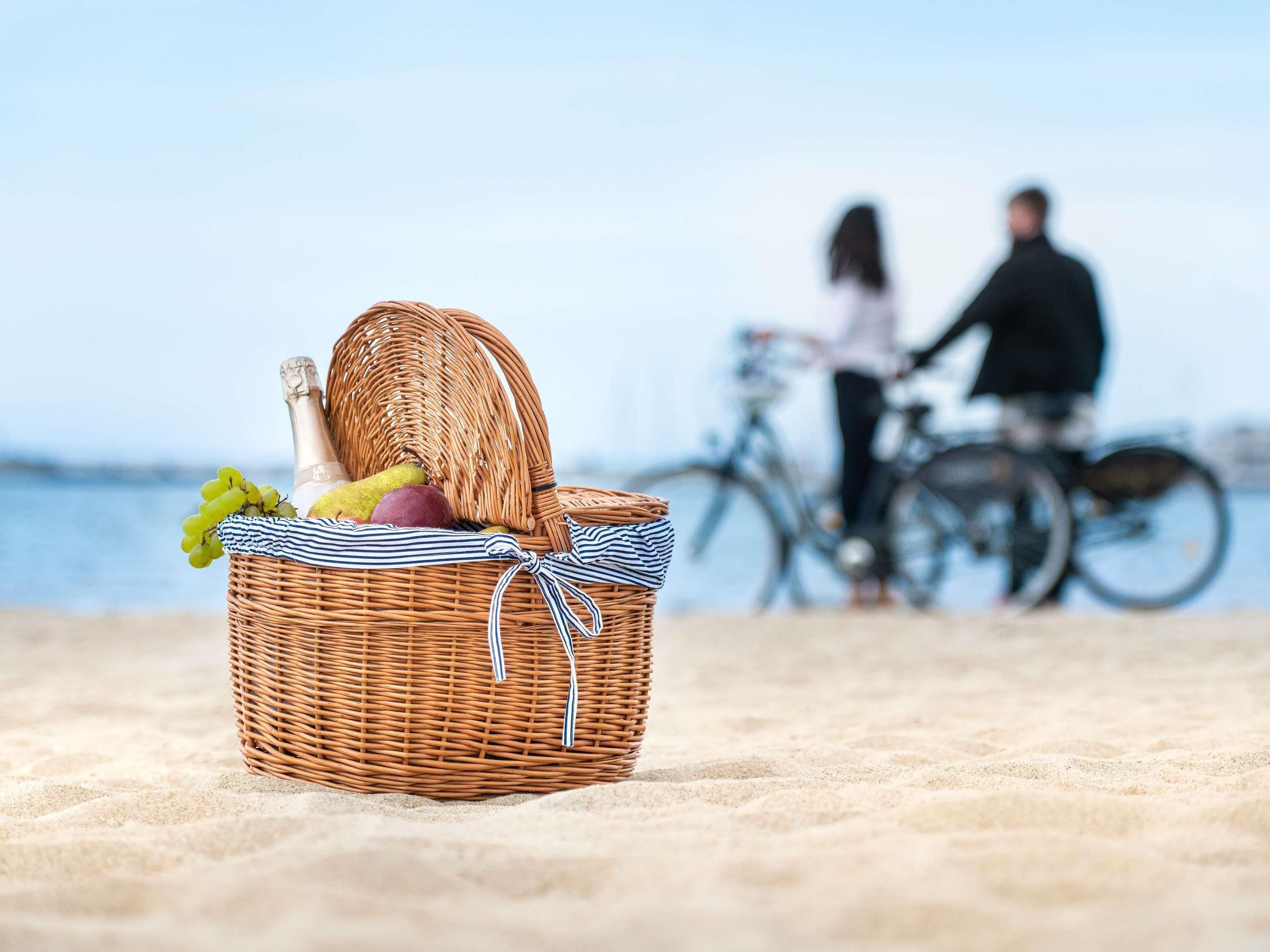 En fletkurv på en sandstrand med en cykel og to personer i baggrunden.