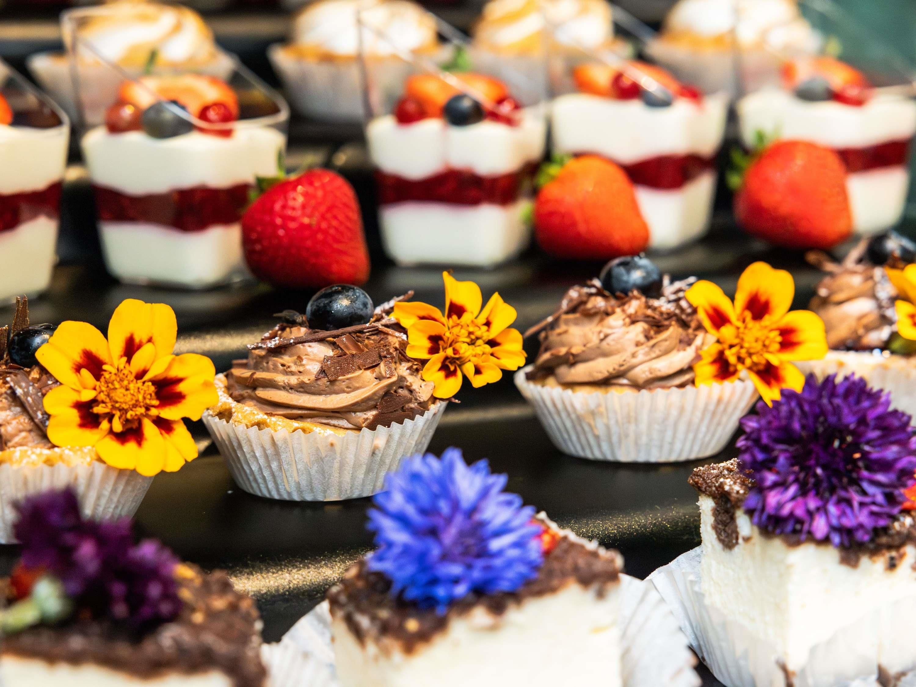 A variety of desserts with fruit and flowers on a tray.
