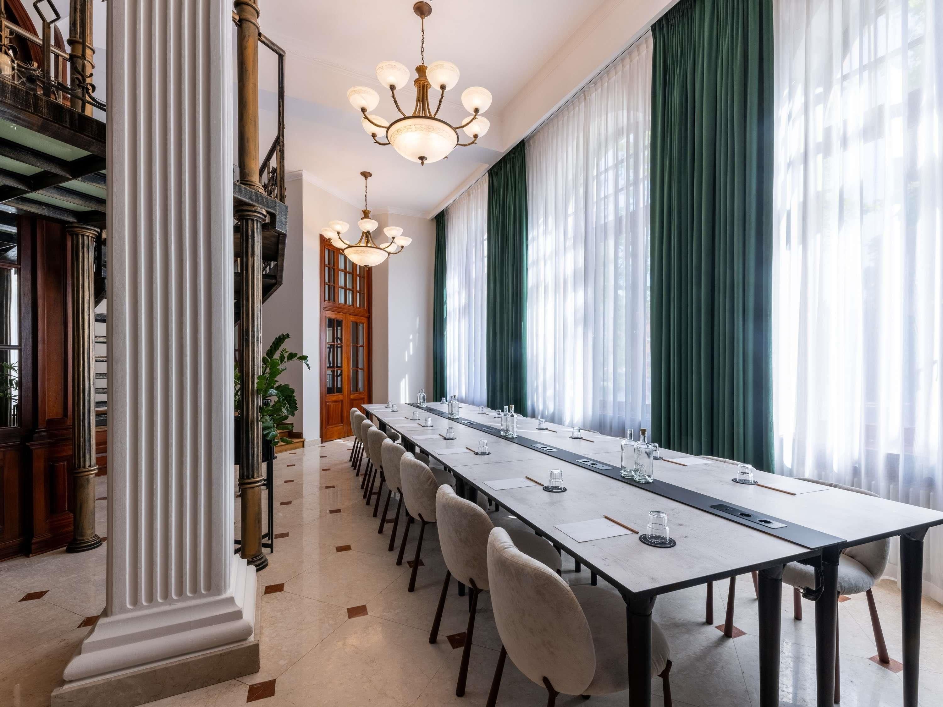 Un salón de conferencias con una mesa larga, sillas y un candelabro.
