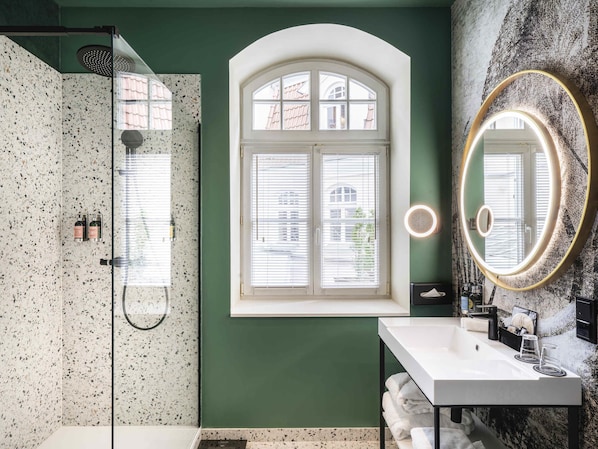 Une salle de bain avec une douche, une fenêtre, un lavabo et un miroir.