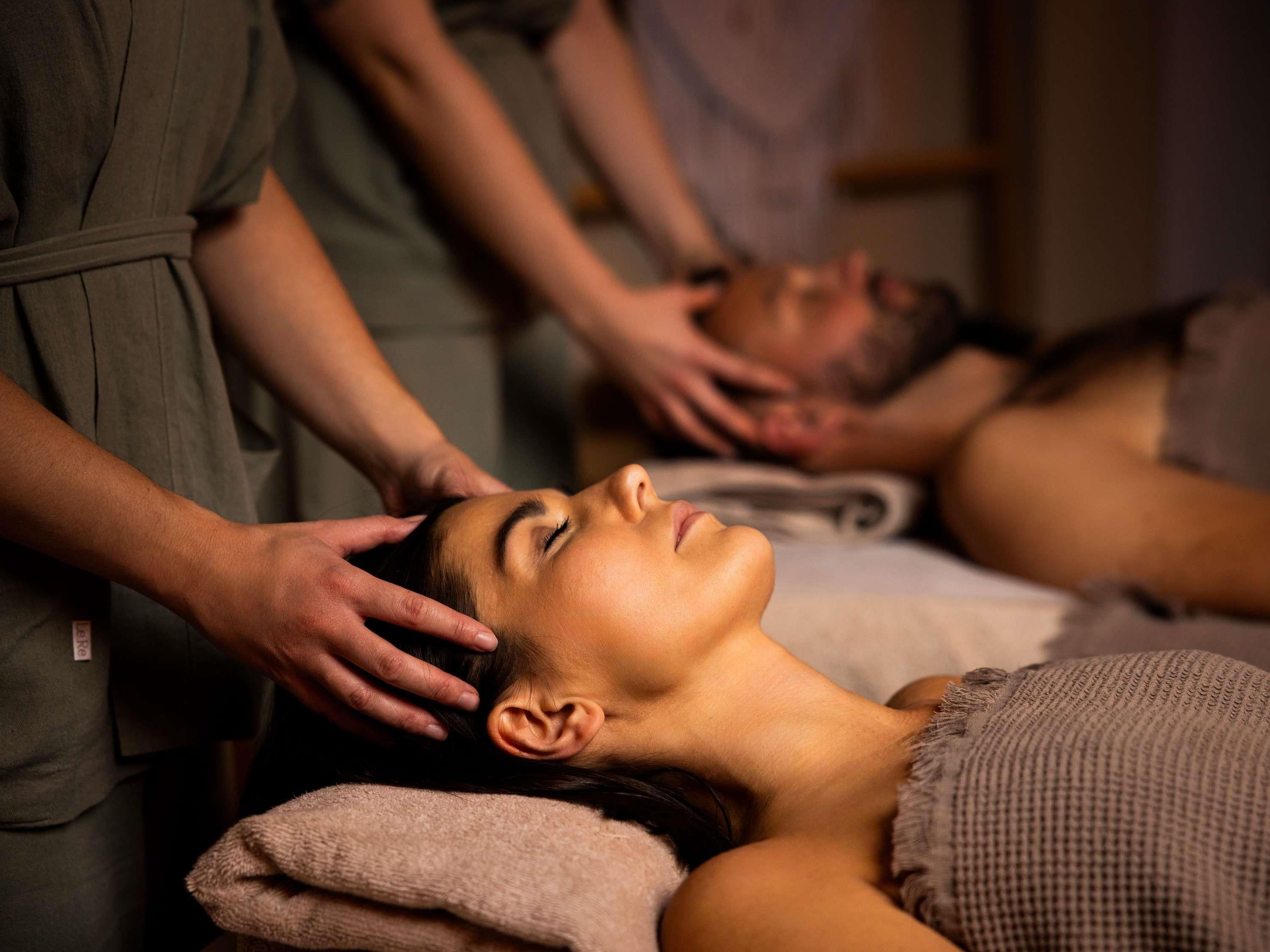 Eine Massageanwendung in einer Wellnessumgebung, ein Klient liegt auf einer Massageliege.