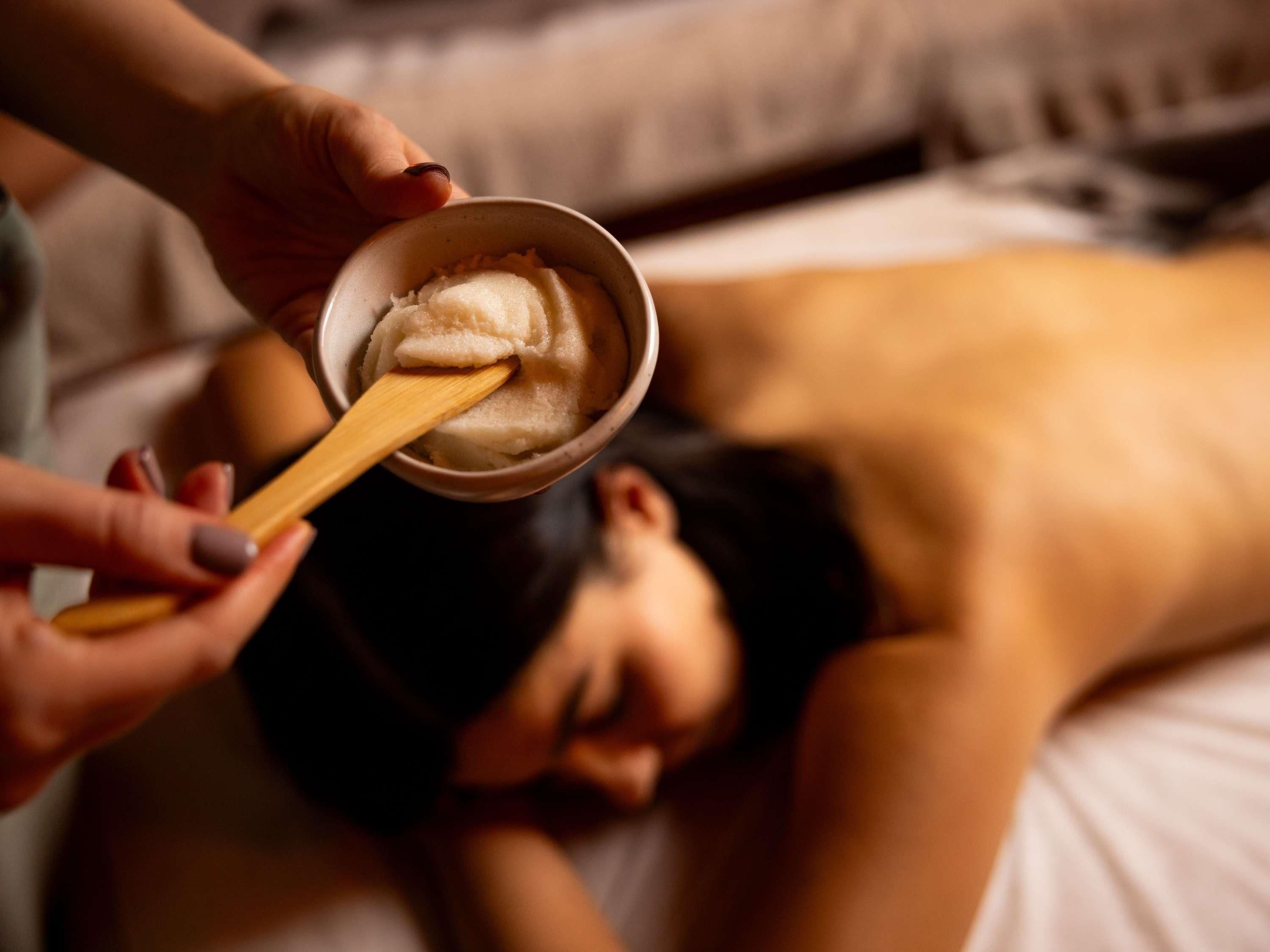 A person lying on a bed receiving a facial treatment.
