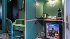 A teal-colored room with a desk, chair, and a refrigerator stocked with beverages. - Rezydent Hotel Sopot - MGallery Collection (Sopot)