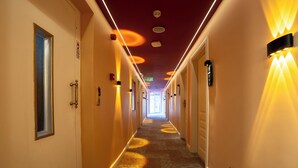 A hotel hallway with carpeted floors, doors on both sides, and wall-mounted light fixtures. - Navoris Hotel (Istanbul)