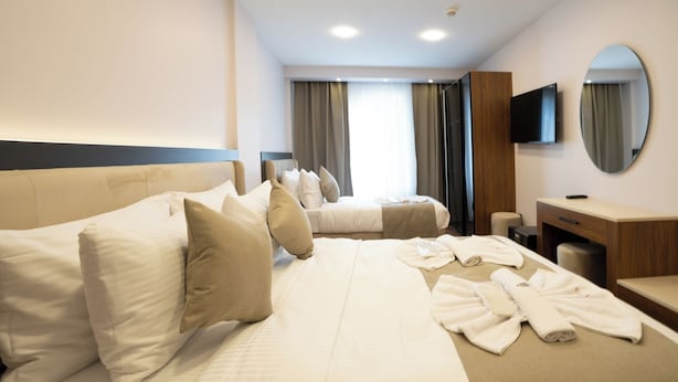 A hotel room with two beds, a desk, a mirror, and a TV. - Navoris Hotel (Istanbul)