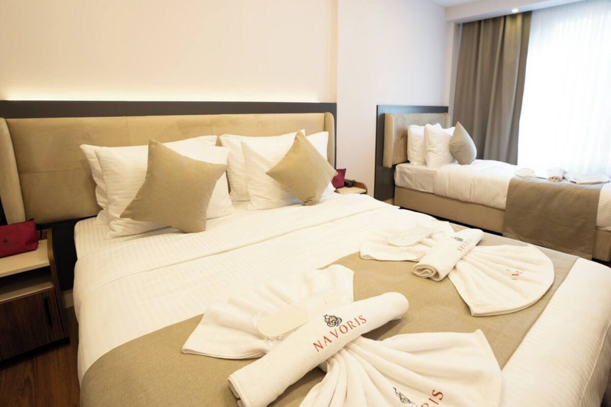 A hotel room with two beds, a nightstand, and a window with curtains.