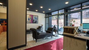 A modern hotel lobby with a red carpet, seating area, and large windows offering a view of the street. - Navoris Hotel (Istanbul)