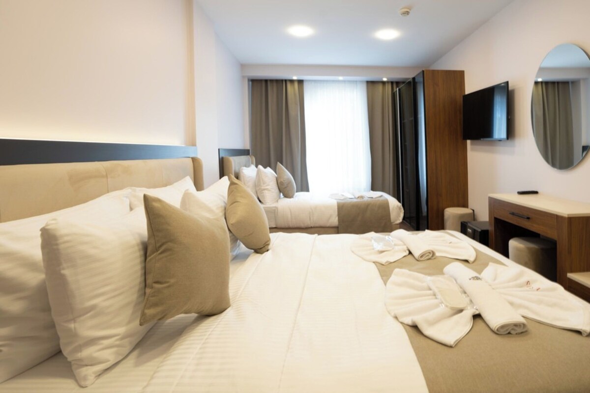 A hotel room with two beds, a TV, a mirror, and a desk.