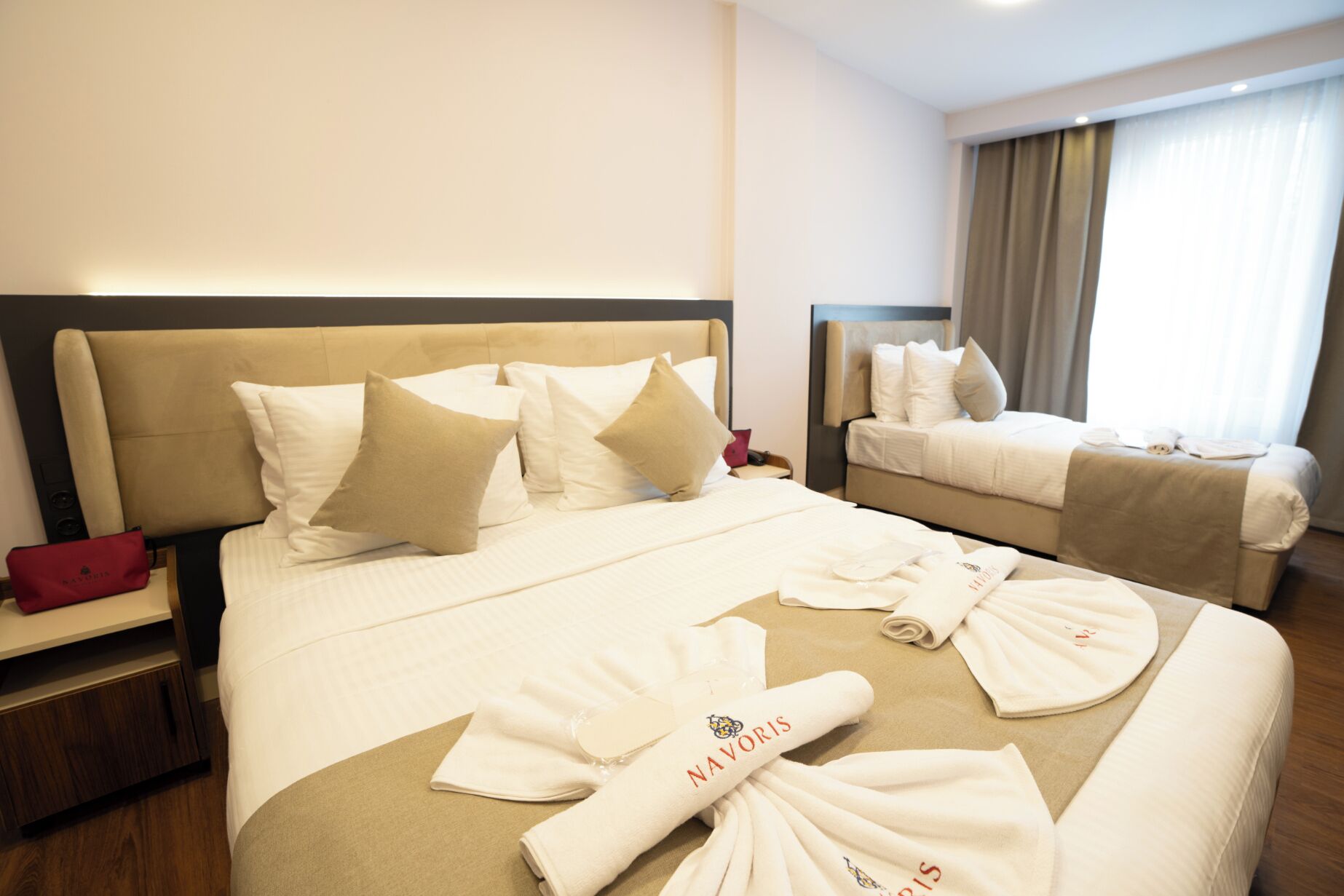 A hotel room with two beds, a nightstand, and a bathroom.