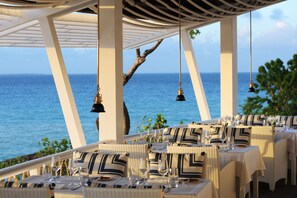 A seaside restaurant with tables set for dining, overlooking the ocean. - Malliouhana Resort Anguilla (West End Village)