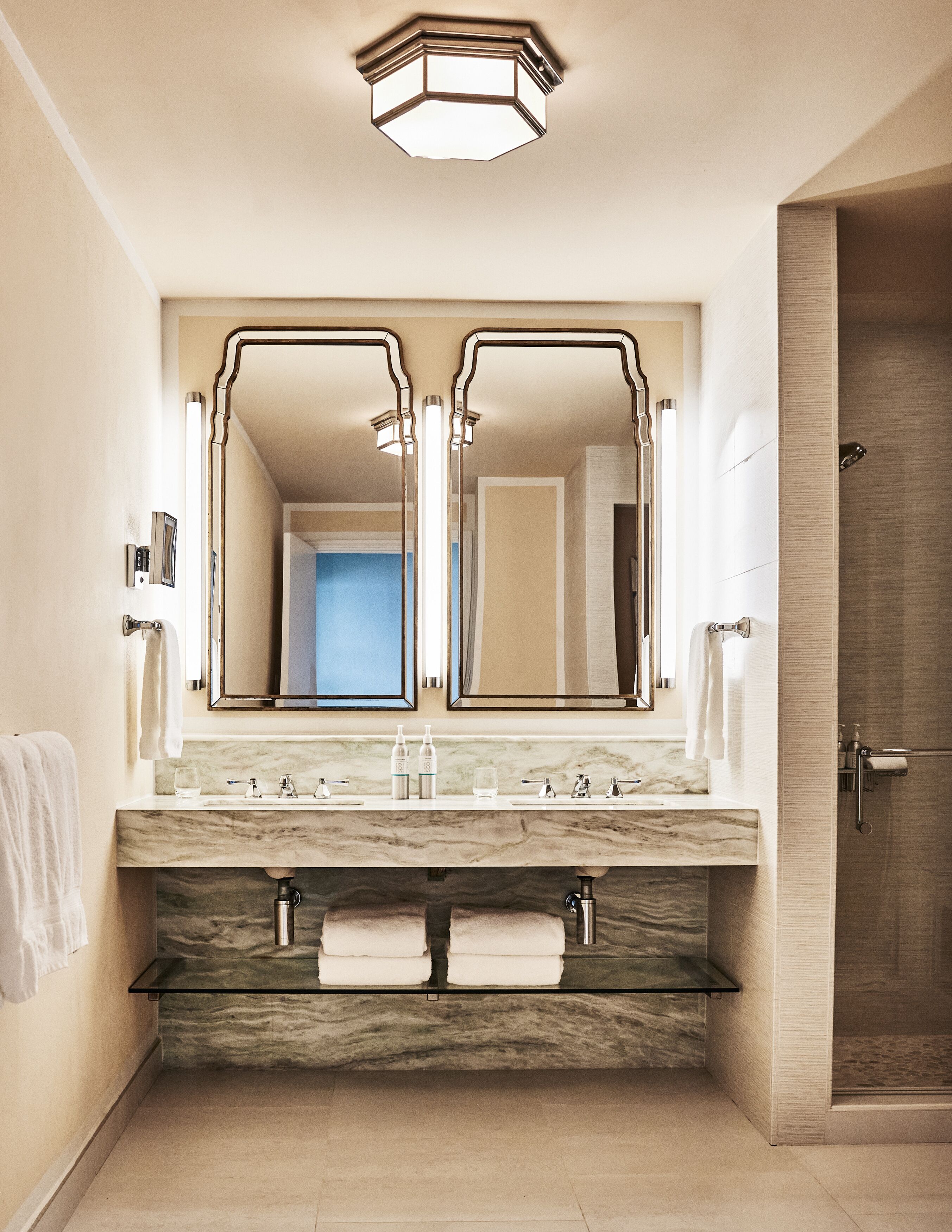 A modern bathroom with a large mirror, dual sinks, and a shower.
