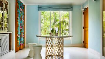 Una habitación con una mesa redonda, un pedestal blanco y una ventana con vistas a zonas verdes.