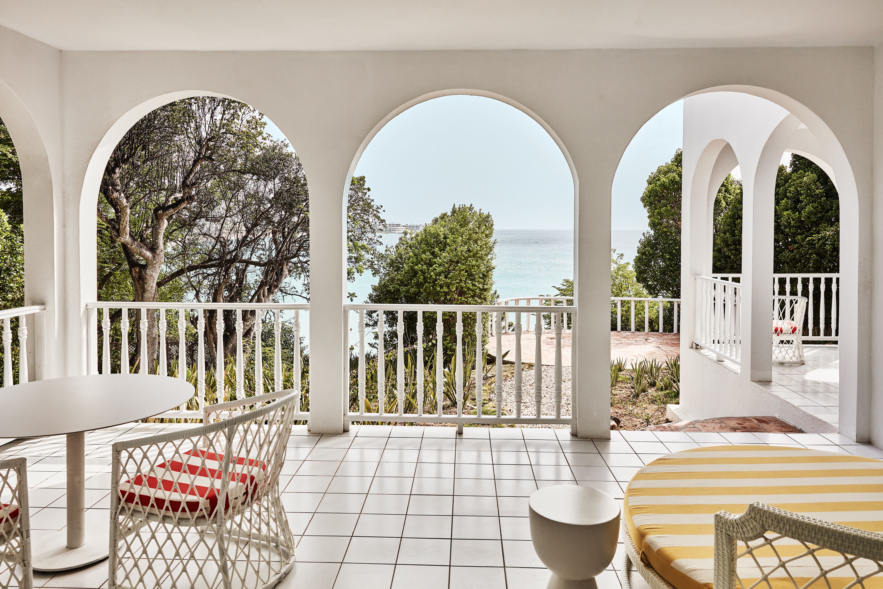 A balcony with white railings, a round table, and a cushioned chair.