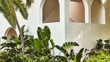 A building with arched windows and a garden with various plants.
