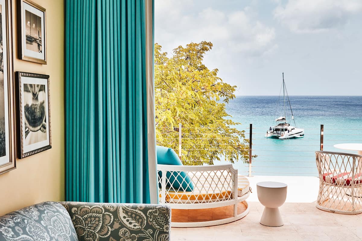 A living room with a sofa, a coffee table, and a view of the ocean and a sailboat.