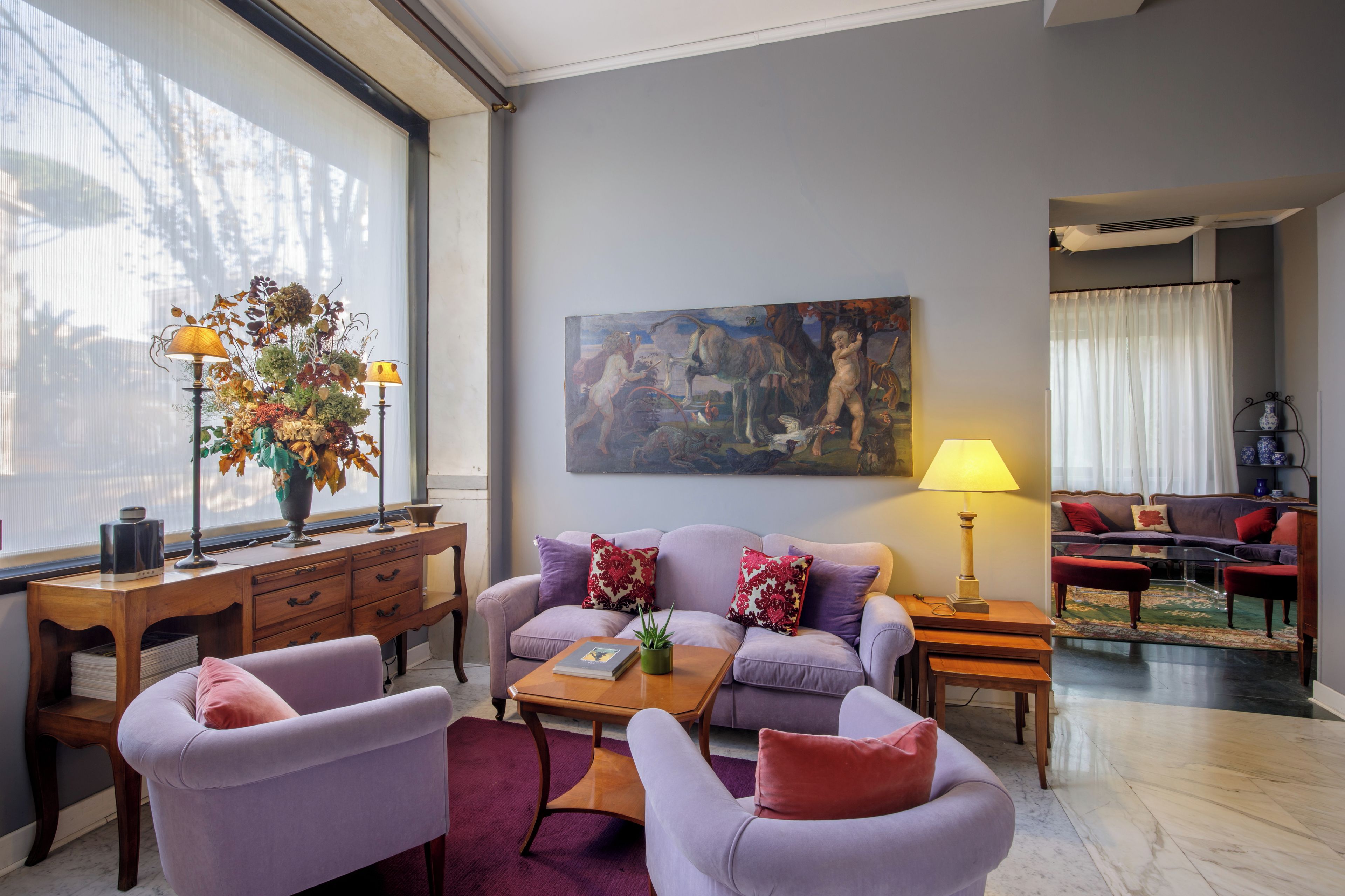Una sala de estar moderna con un sofá, sillones, una mesa de centro y un cuadro en la pared.