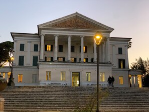 A large white building with columns and a central entrance, surrounded by steps and street lamps. - Fenix Hotel (Rome)