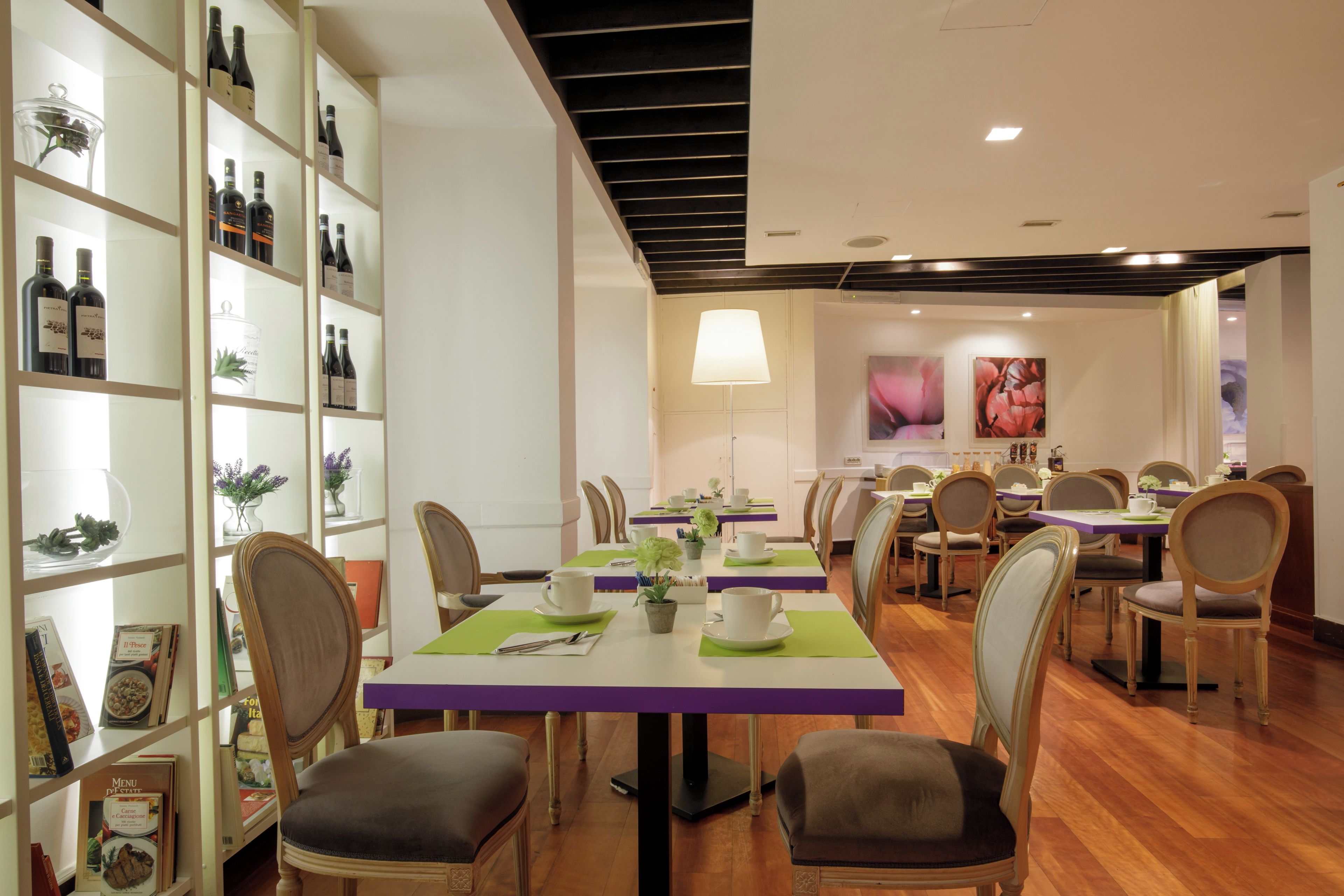 Un restaurante con una larga mesa de comedor, sillas y una estantería con botellas de vino.