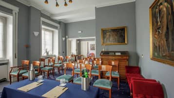 Quarto com uma mesa azul posta para refeições, cadeiras de madeira, um sofá vermelho e um quadro na parede.