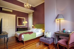 Une chambre d’hôtel avec un lit, une table de chevet, une chaise, un bureau et un miroir au mur.