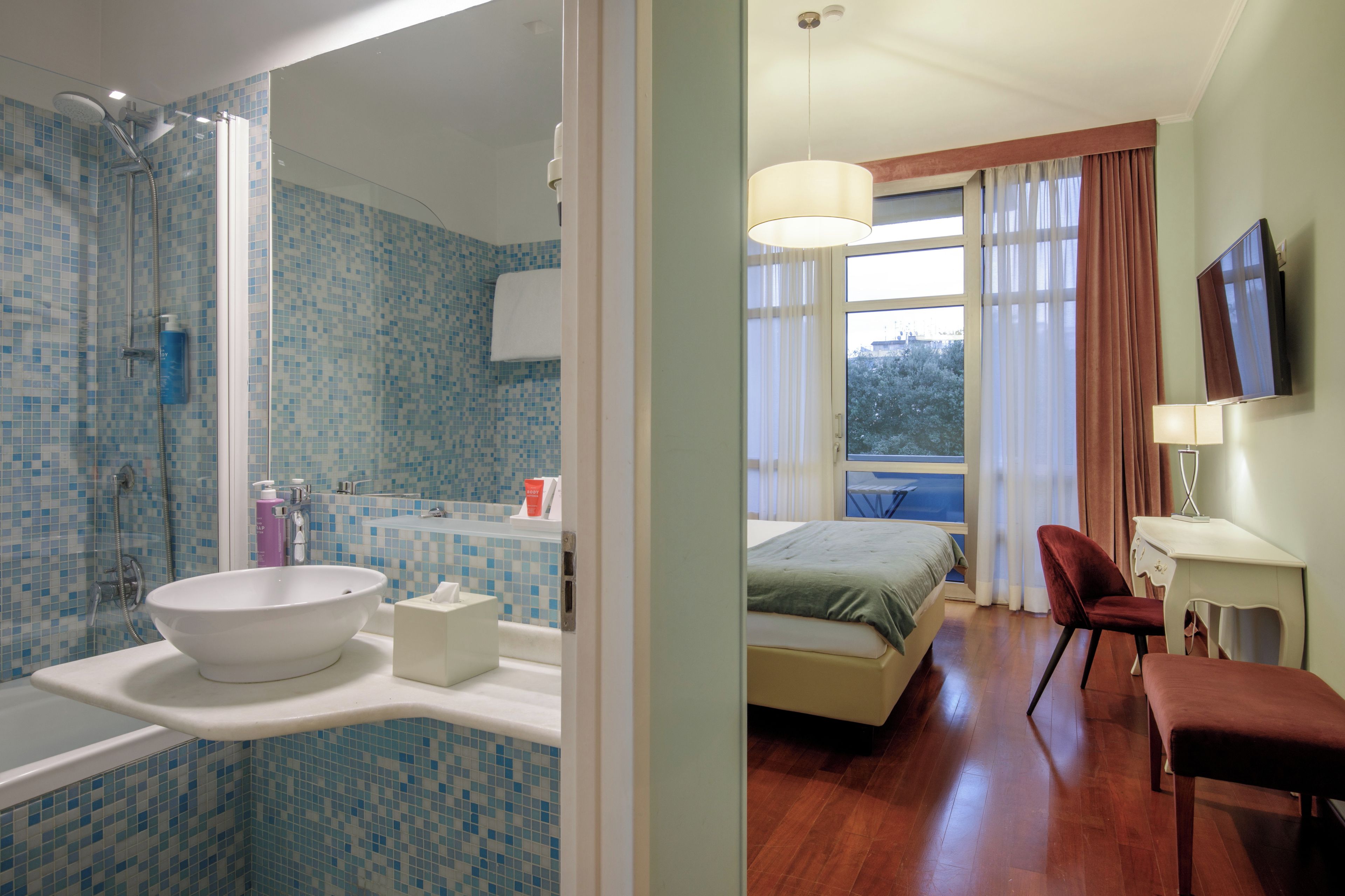 A modern bathroom with a large white sink, a shower, and a mirror.