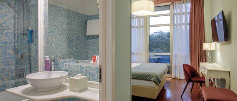 A modern bathroom with a large white sink, a shower, and a mirror.