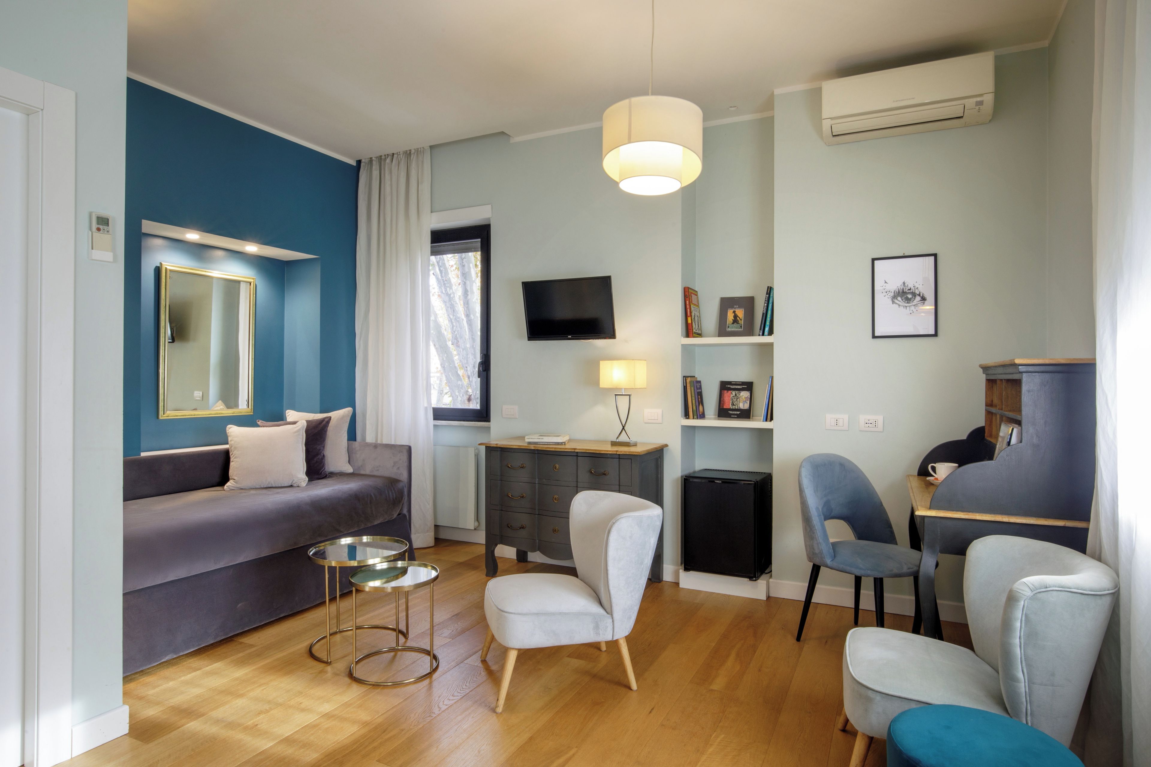 Ein modernes Wohnzimmer mit einer Couch, Sesseln, einem Couchtisch, einem Fernseher und einem Bücherregal.