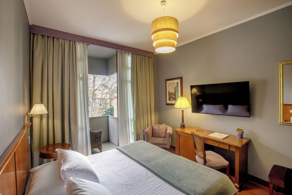A hotel room with a bed, a desk, a chair, a TV, and a window with curtains. - Fenix Hotel (Rome)