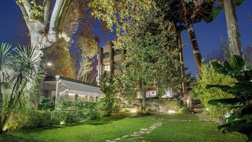 Un jardin bien entretenu, avec un chemin de pierre menant à un bâtiment doté de nombreuses fenêtres et de balcons.