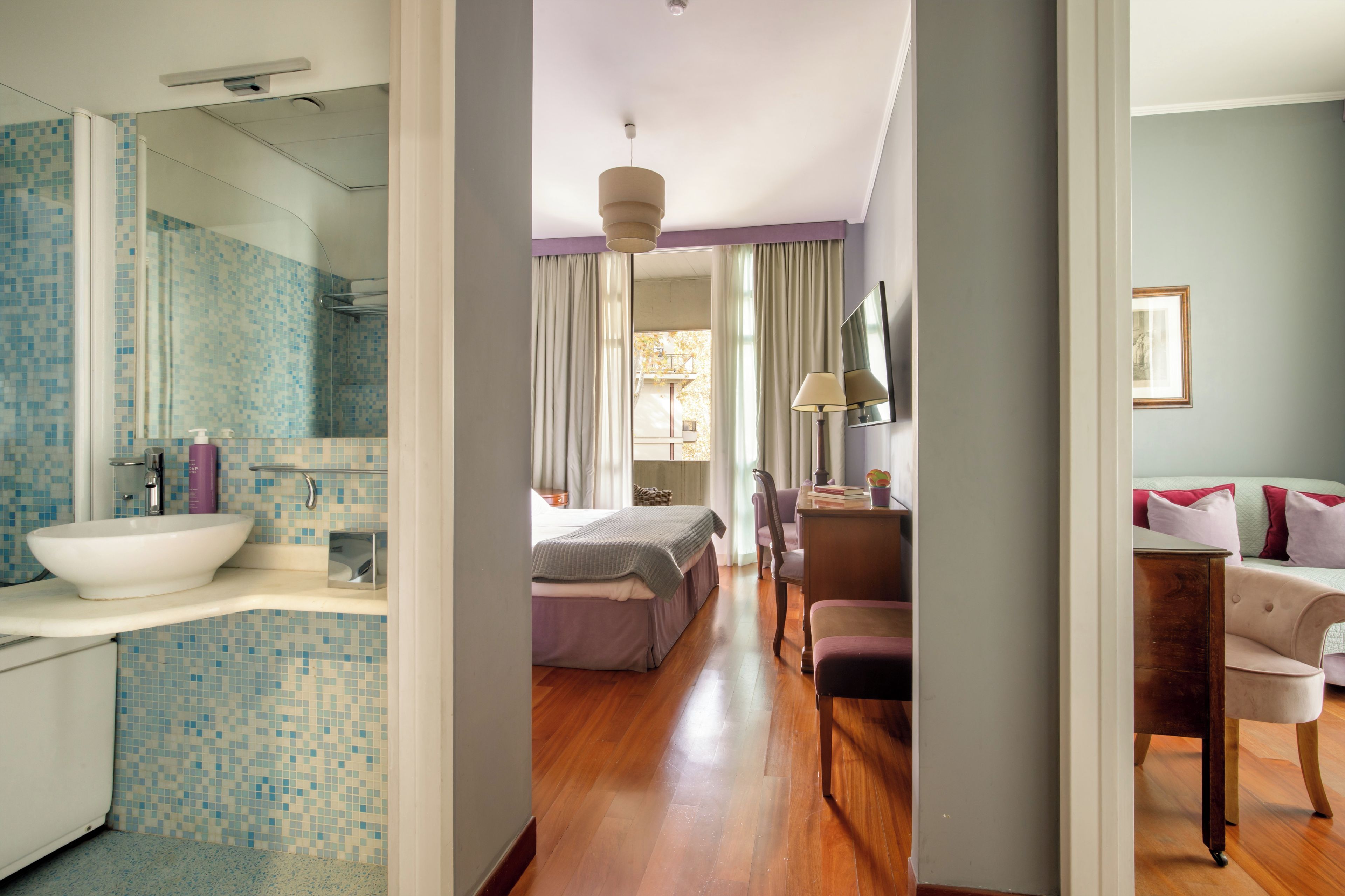 A hotel room with a bathroom, a bed, a desk, and a chair.