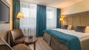Une chambre d’hôtel avec un lit, deux chaises, une petite table et un téléviseur.