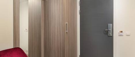 A room with a wardrobe, a door, and a red chair.