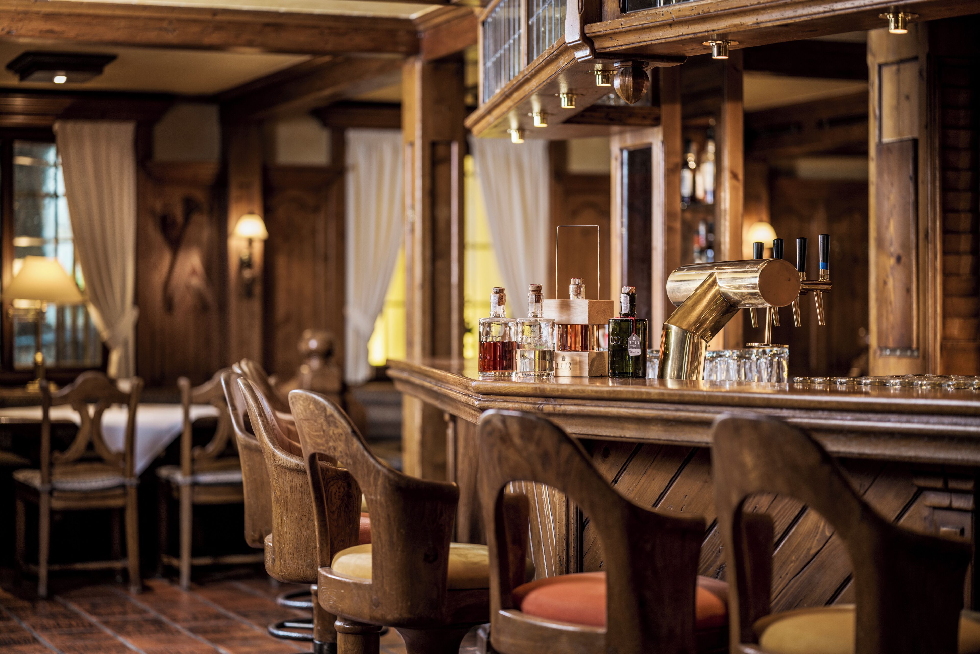 Uma área de bar com cadeiras de madeira, balcão e espelho.