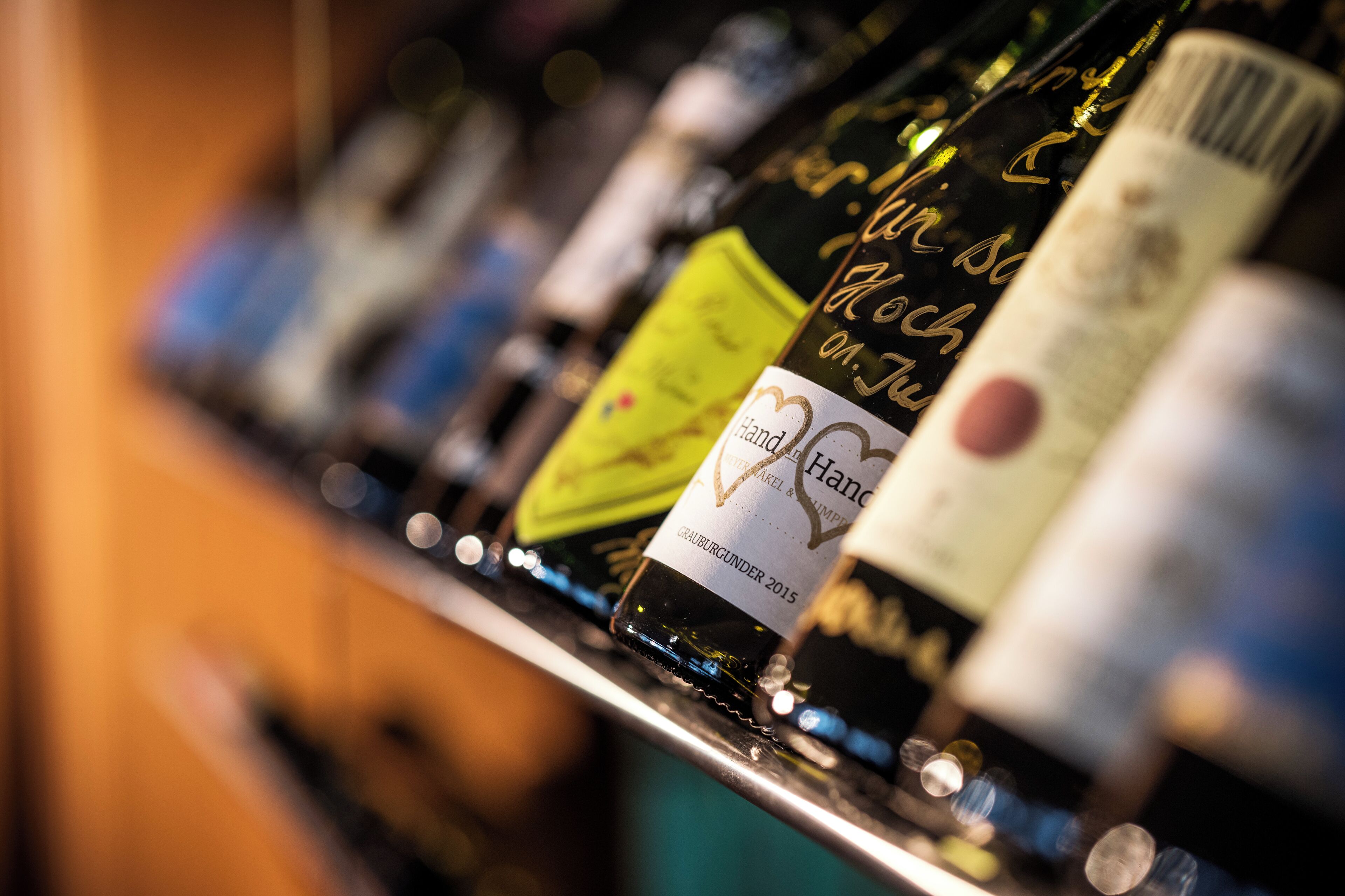 Primer plano de botellas de vino con etiquetas en una estantería.