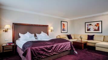 Habitación de hotel con una cama grande, un sofá, una mesita de centro y dos lámparas de pared.