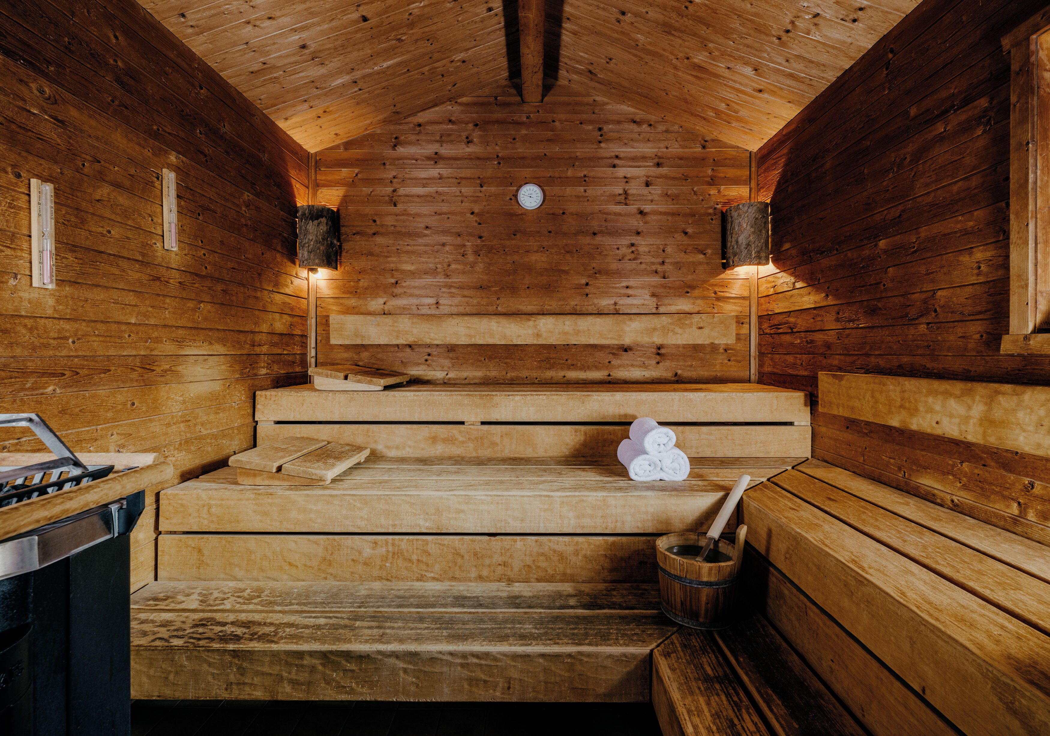 Uma sauna de madeira com bancos, um relógio e um balde.