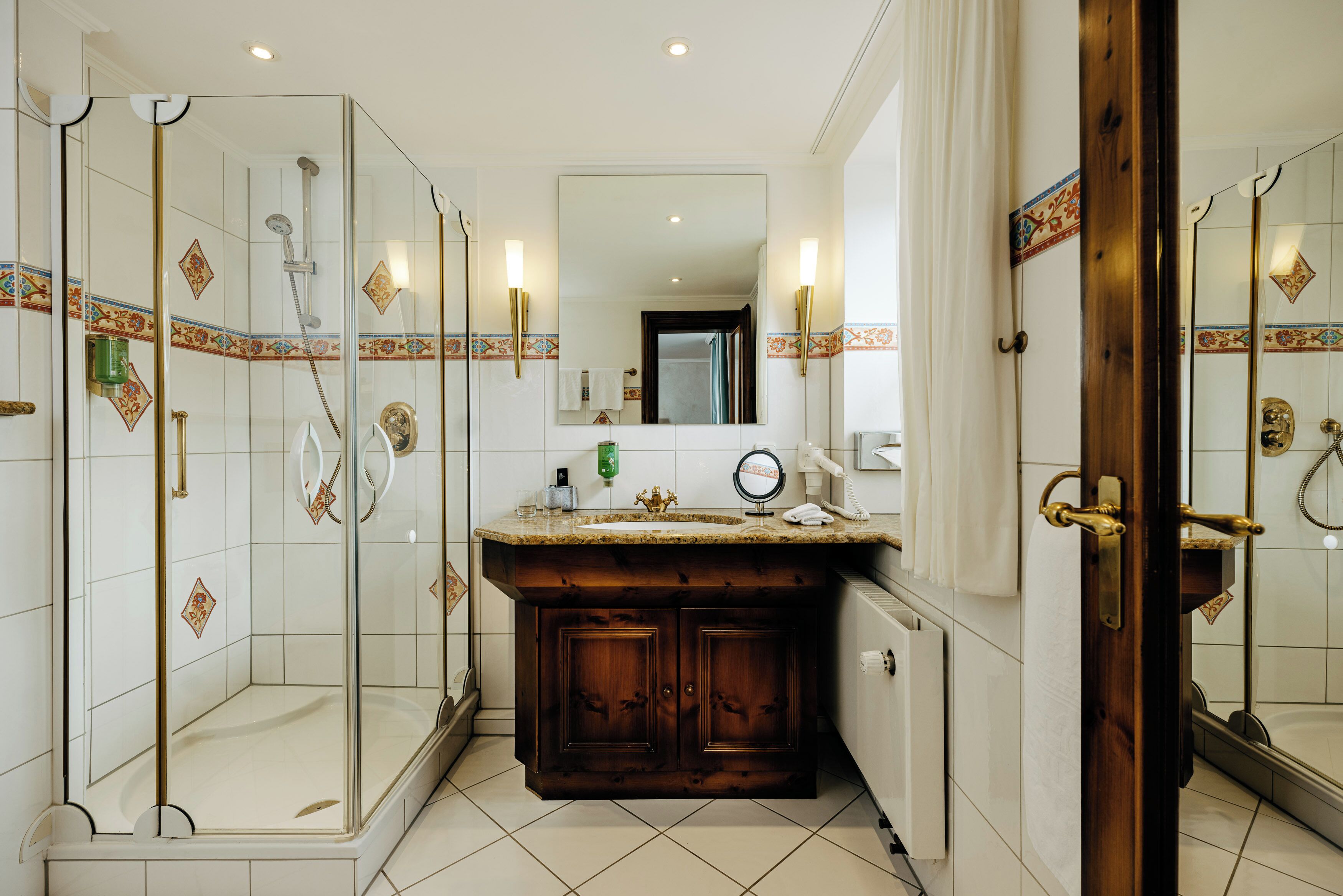 A bathroom with a glass-enclosed shower, a vanity with a mirror, and a sink.