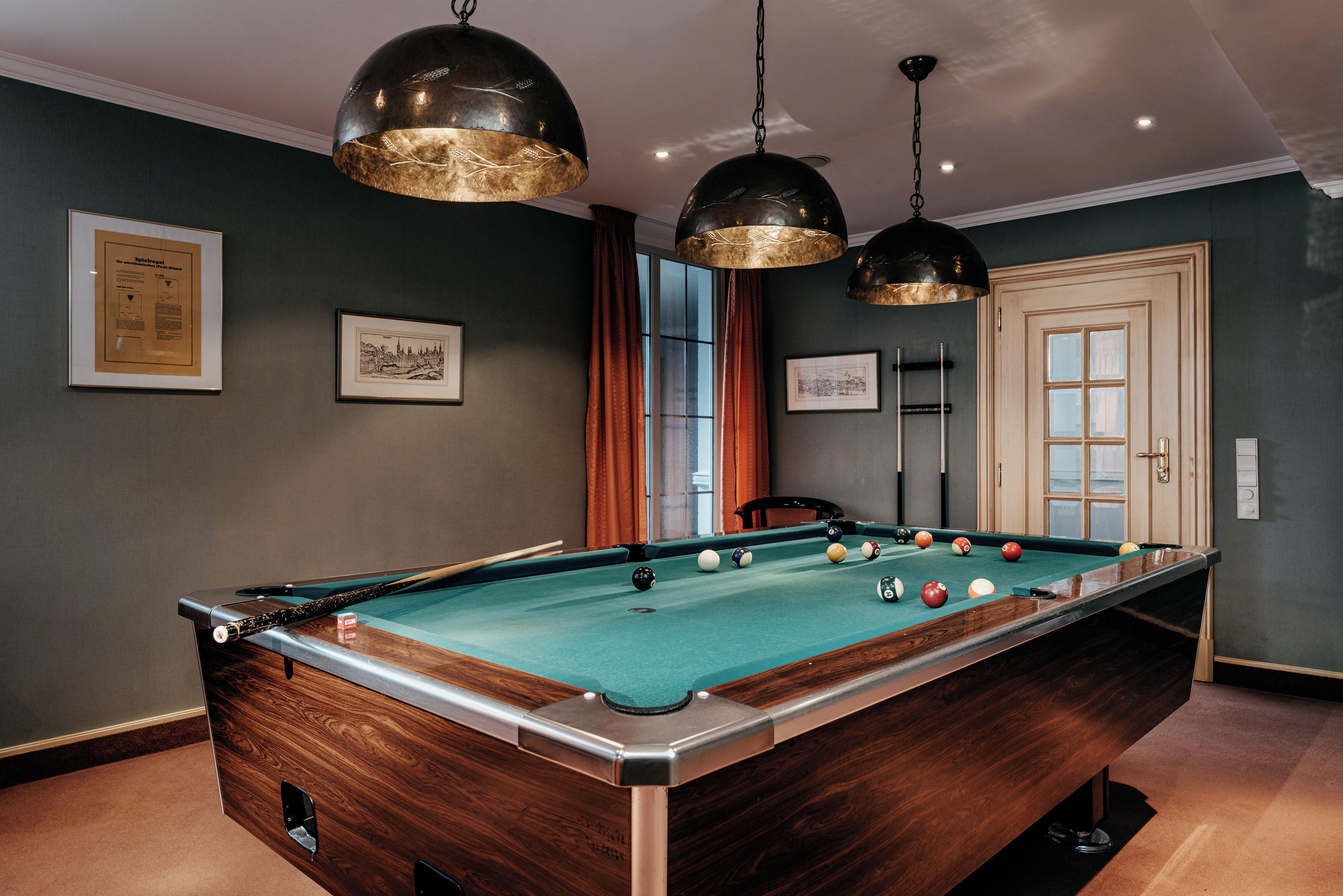 Une table de billard avec des billes, un certificat encadré accroché au mur et une porte avec une fenêtre.