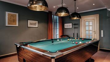 A pool table with balls, a framed certificate on the wall, and a door with a window.